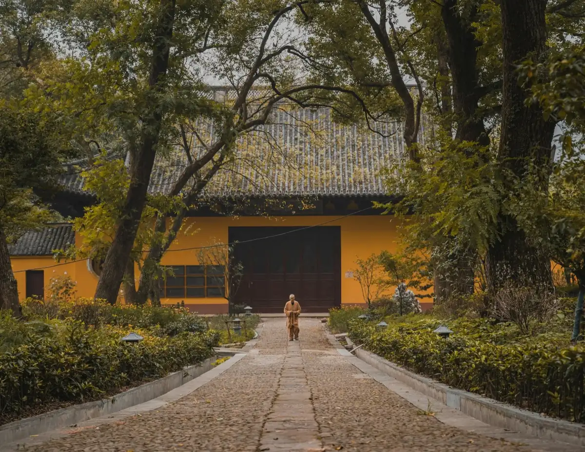 A solitary figure walking through a quiet temple garden in China
