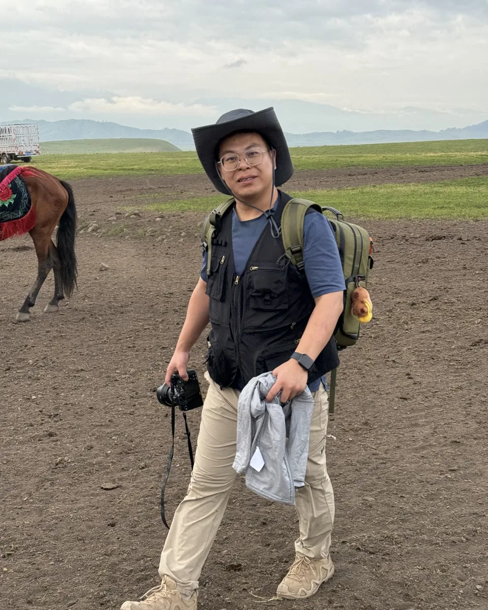 Patrick, co-founder of Limina China, carrying a camera during route research in the Chinese grasslands