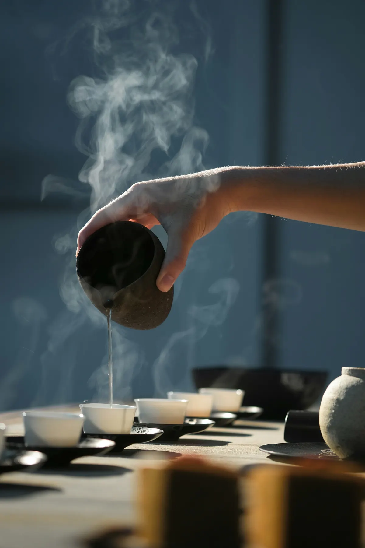 Hand pouring tea into small cups during a Chinese tea ritual
