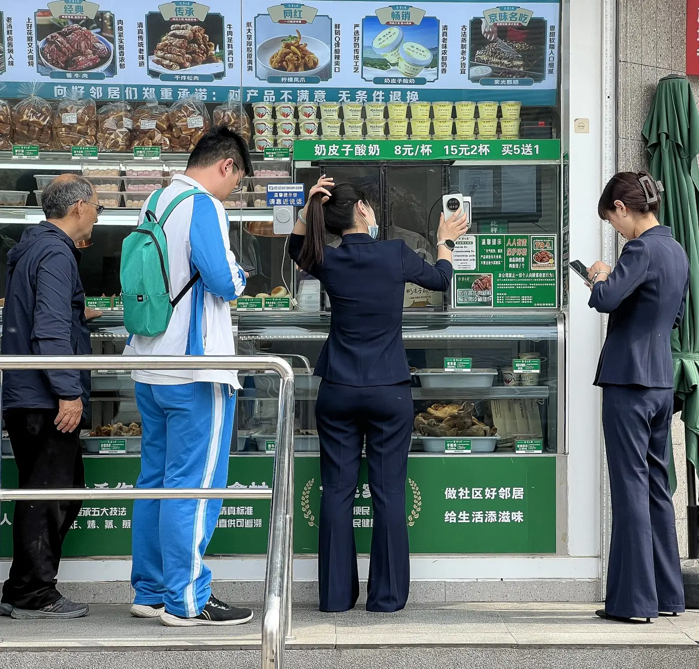 A customer holding her phone toward the payment reader at a Ziguangyuan food counter in Beijing