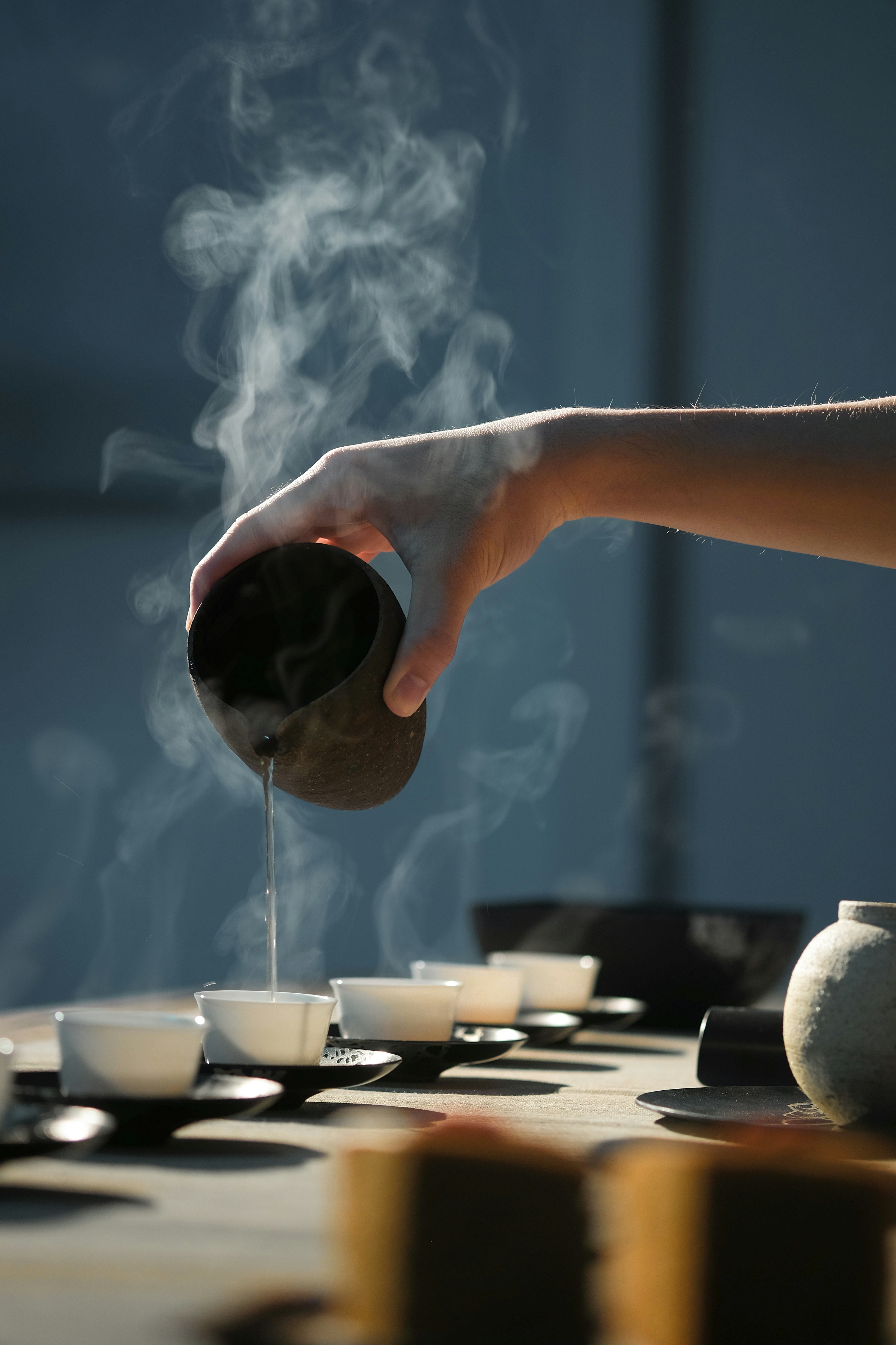 Hand pouring tea into small cups during a Chinese tea ritual