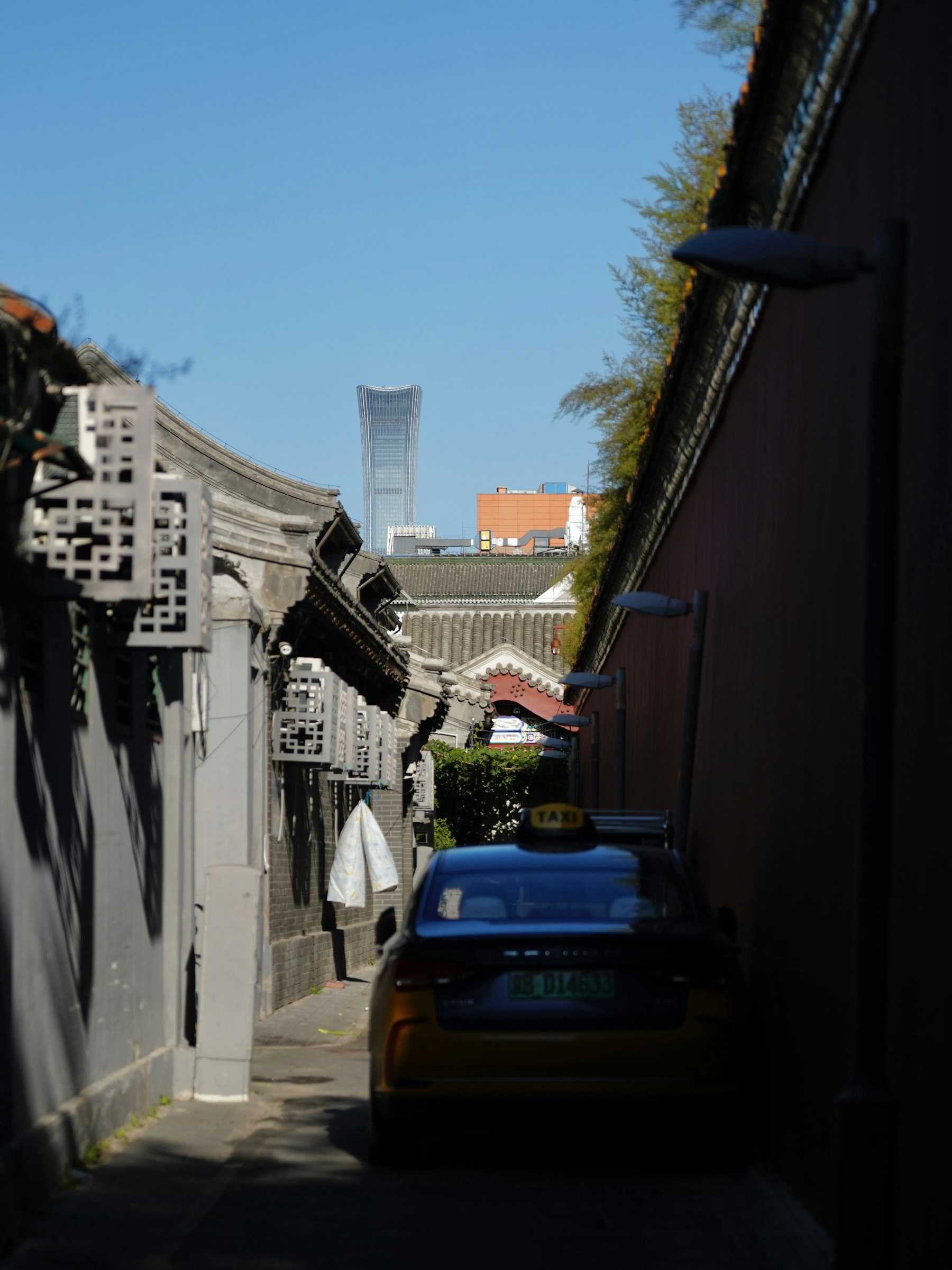 A narrow Beijing hutong lane with layered urban texture