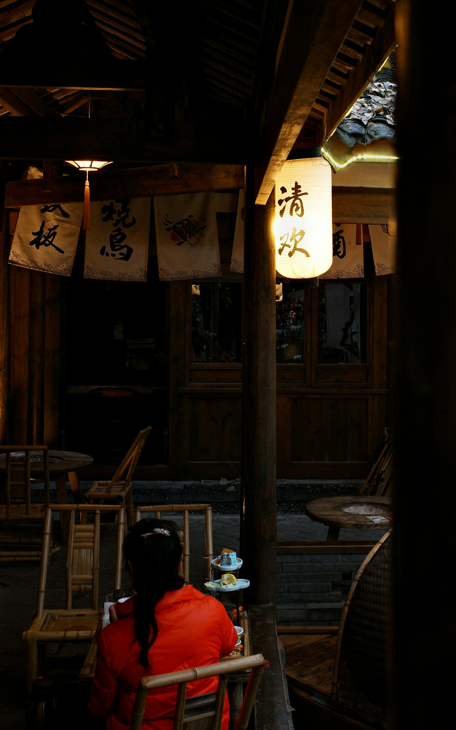 A woman seated in a warmly lit Chinese teahouse